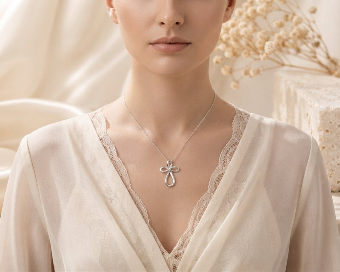 Close-up of a person wearing the sterling silver infinity cross necklace, showing the pendant resting elegantly against their collarbone.