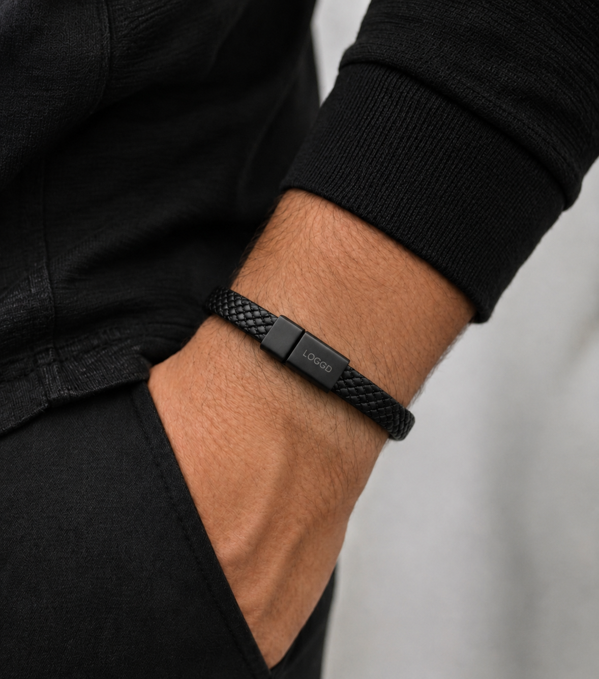 Black braided bracelet on a wrist with a neutral background
