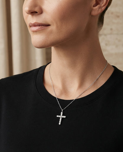 Close-up of a person wearing the sparkling pavé cross necklace, showing the pendant resting gracefully against their collarbone.