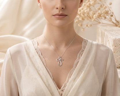 Close-up of a person wearing the sterling silver infinity cross necklace, showing the pendant resting elegantly against their collarbone.